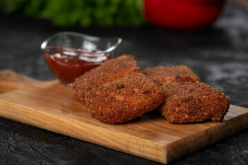 chicken nuggets and sauce on a board .