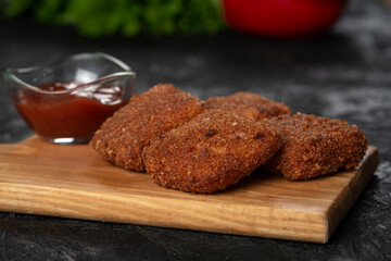 chicken nuggets and sauce on a board .
