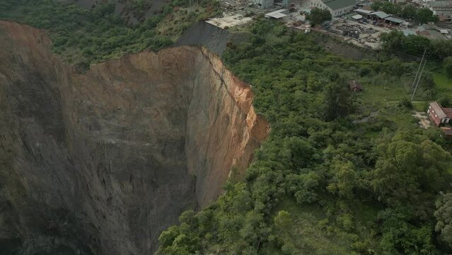 Aerial tilt reveals scaling of vertical rock cliff in open pit mine