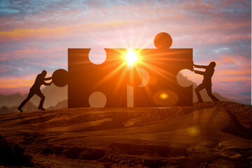 Teamwork, partnership and cooperation. Business concept of teamwork with puzzle. Silhouettes of two...