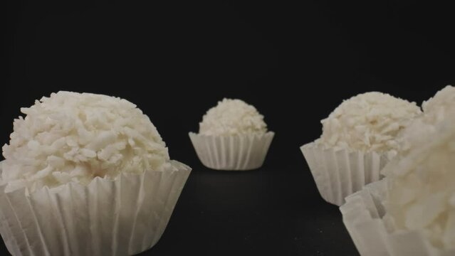 Coconut balls in muffin cup liners. The camera passes in between. Dolly shot with macro probe lens. Slider movement.