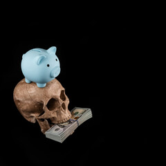 Model of a human skull, a pack of American dollars and a blue piggy bank