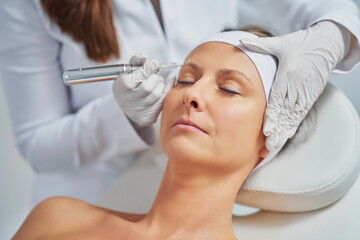 Obraz na płótnie Canvas Woman having permanent eyebrows cosmetology treatment in salon