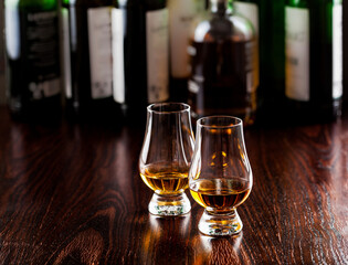 Bottles and glass of whisky spirit brandy on dark brown background