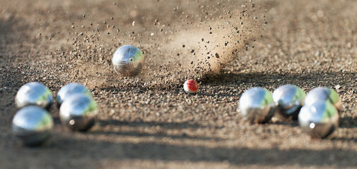 Petanque ball boules bowls on a dust floor, photo in impact. Game of petanque on the ground. Balls...