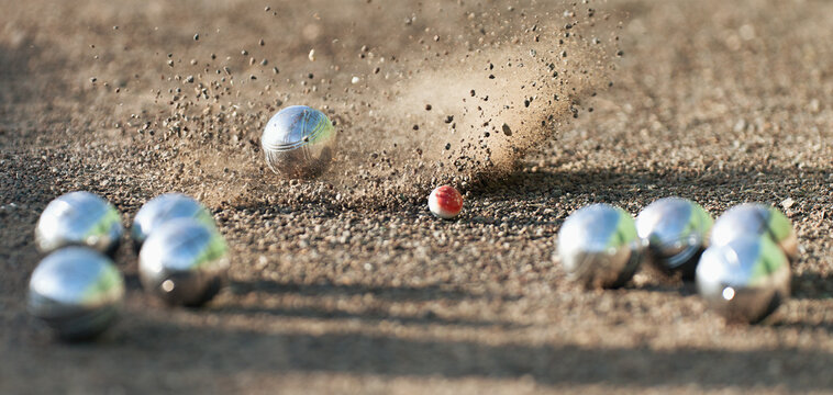 Petanque ball boules bowls on a dust floor, photo in impact. Game of petanque on the ground. Balls and a small wood jack