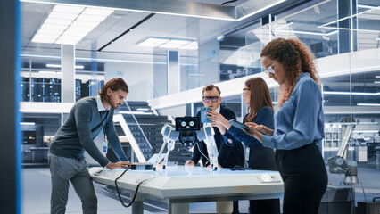 Portrait of Diverse International Team of Industrial Robotics Engineers Gathered Around a Table With a Robot Dog. Scientists Use Computers and Connect a Motherboard to a Mobile AI Four-Legged Robot.