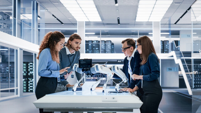 Portrait of a Young Team of Multicultural Engineers Use Computers, Insert a Circuit Board, Analyze and Discuss How a Futuristic Robot Dog Works. High Tech Research Laboratory with Modern Equipment.