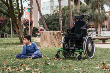Child with a disability relaxing sitting on a grass in a public park.