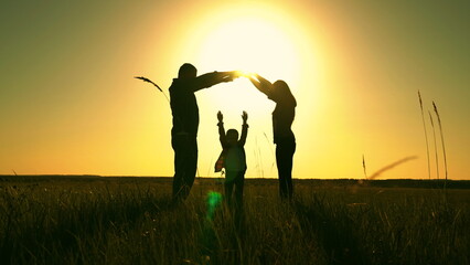 Happy family shows house with their hands, symbol of safety, comfort for child, sunset. Happy family mother father daughter, son, kid, dream to build house, mortgage for family. Silhouette of teamwork