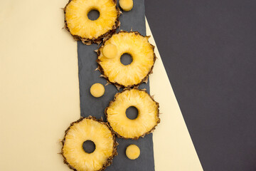 Raw pineapple slices are placed on a black background with yellow