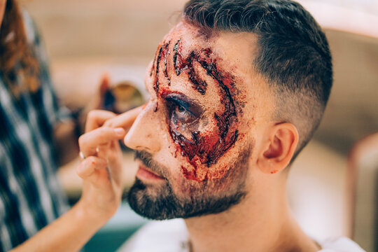 Man with makeup on his face with wounds and blood.