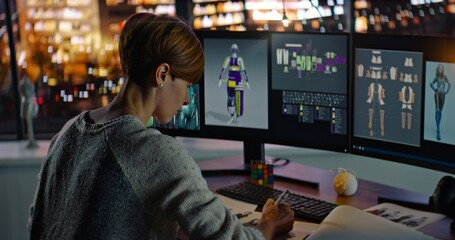 Female Fashion Designer Working in Her Home Studio. Young Woman Creating 3D Virtual Models on Computer and Makes Corrections to Paper Sketches. Night City Background