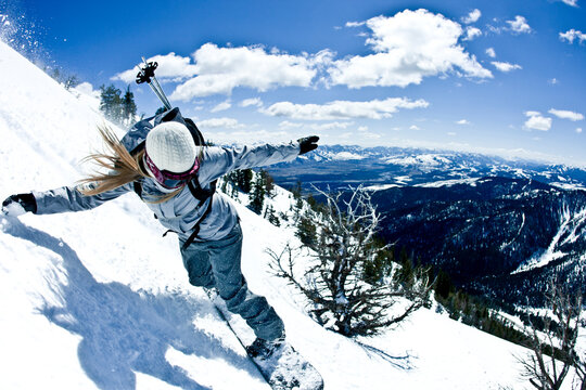 Woman snowboarding in mountains.