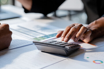 Fototapeta premium Businessman using a calculator to calculate numbers on a company's financial documents, he is analyzing historical financial data to plan how to grow the company. Financial concept.