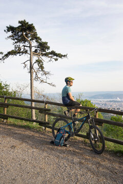 Mountain biker resting while sitting on wooden railing