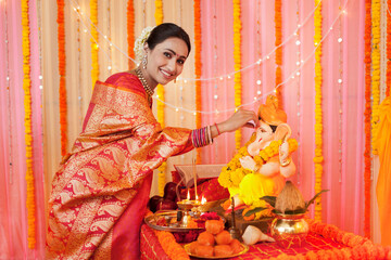 Portrait of an Indian woman putting tilak on Lord Ganpati's idol - Festival celebration. Stock...