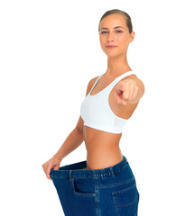 Health, weight loss and woman pointing hand with jeans and tummy tuck with skinny waist, isolated on white background. Smile, healthcare and wellness, happy girl with liposuction, diet and big pants.