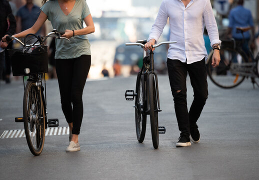 Couple walking with their bikes in summer city