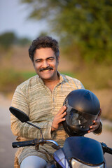 Indian rural man using helmet while drive on motorbike