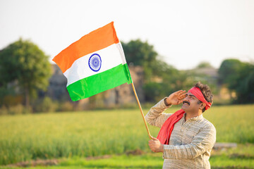 indian farmer saluting to national flag at agriculture field.