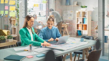 Obraz premium Portrait of Two Caucasian Smiling Women Collaborating and Working on a Laptop Computer in a Bright Office. Two Female Data Analysts Developing a Project and Preparing a Presentation. Teamwork Concept
