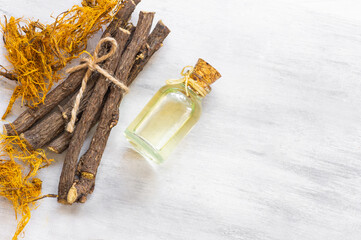 Glass bottle of licorice root essential oil with liquorice fiber on rustic background ( glycyrrhiza...