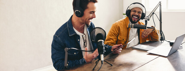 Cheerful podcasters laughing and having a good time in a studio