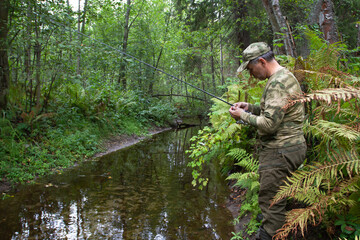 Fototapeta premium a fisherman stands near a small forest river