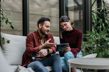 Business people sitting at the office, talking and using a tablet.