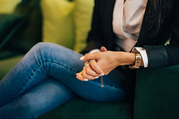 Hands of a businesswoman, sitting on the couch, elegantly dressed.