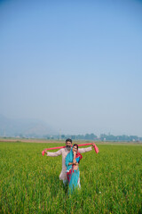 Indian farmer with wife giving expression at field.
