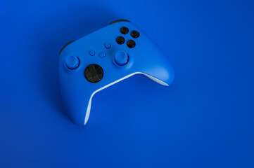 Modern blue gamepad on a blue background, game controller for video games, flat lay, copy space.