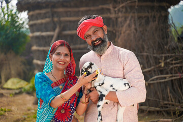 Indian farmer couple holding and caring of goat baby.
