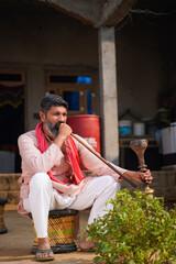 Indian rural man smoking traditional hukka at home.