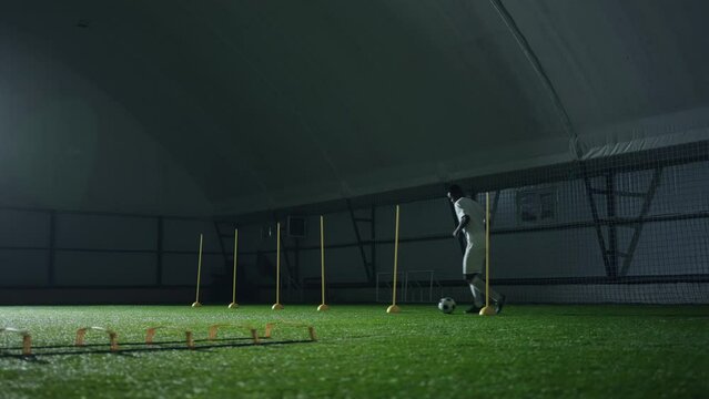 adult black soccer player training in indoor arena, sportsman in football uniform running with ball
