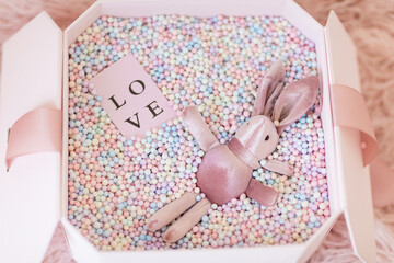 Gift box with pink rabbit. Greeting card Festive holiday pastel backdrop. Birthday congratulations....