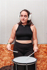 woman with a drum and ear protection playing in a sound-proof room