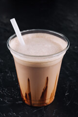 milkshake in a plastic cup on black background