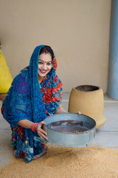 Indian rural woman cleaning wheat at home