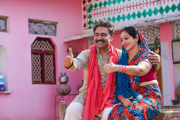 Fototapeta na wymiar indian farmer with wife showing thumps up at home.