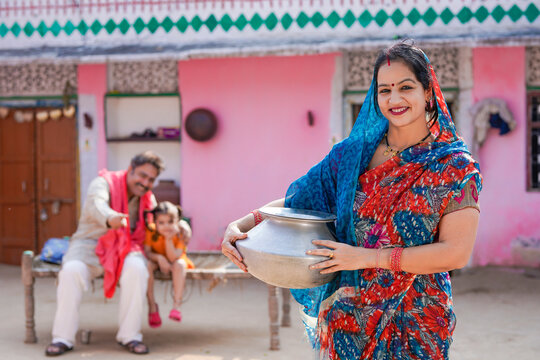 Indian rural woman holding water pot at home.