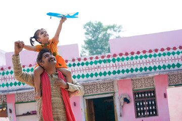 Indian farmers little girl playing with airplane toy with parents