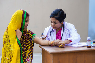 Indian woman doctor injecting to rural woman at clinic