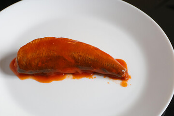 Sardines in tomato sauce on a white plate. Canned sardines.