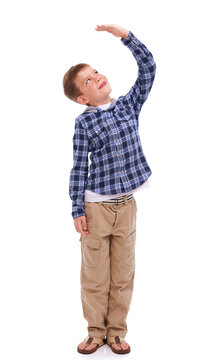 Children, growth and mockup with a boy measuring his height in studio isolated on a white background. Kids, hand and wall with a male child growing up to be tall on blank space for development
