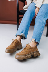 Close-up of female legs in blue jeans and suede brown sneakers. Women's leather casual sneakers