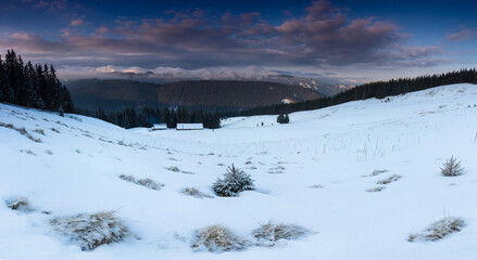 Amazing panoramic landscape  winter mountains at sunrise. View of dramatic overcast sky and distance snow capped peaks. Carpathian mountains range. Europe.