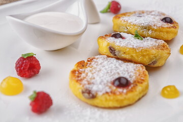 Curd cheesecakes with sour cream and berries, on a white background