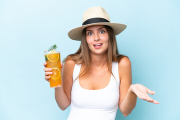Young beautiful woman holding a cocktail isolated on blue background with shocked facial expression